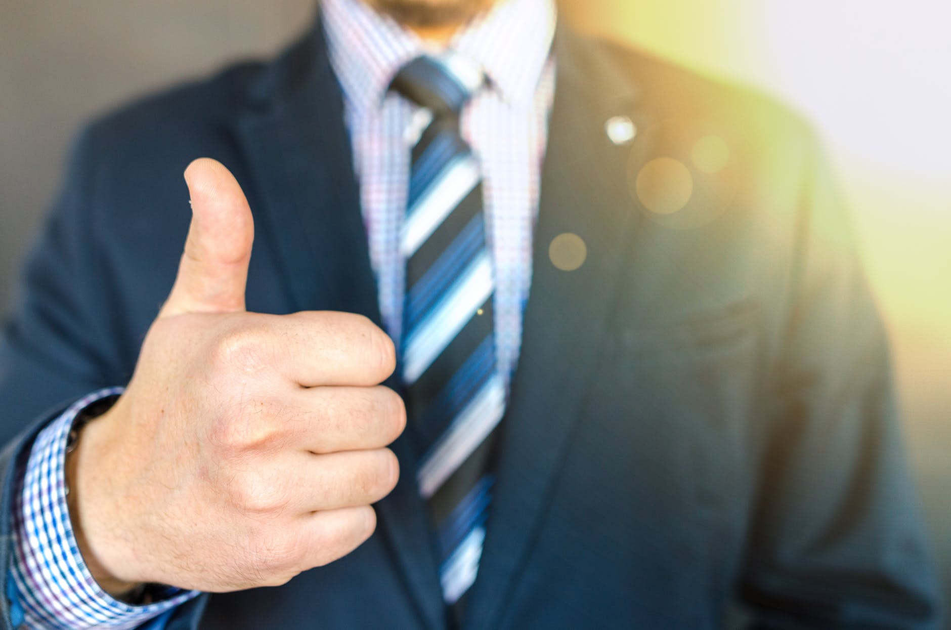 close up photo of man wearing black suit jacket doing thumbs up gesture
