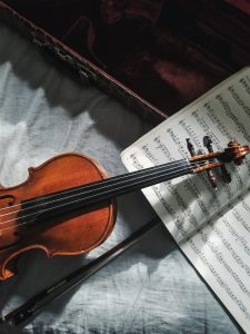 A violin next to a sheet of music and violin case