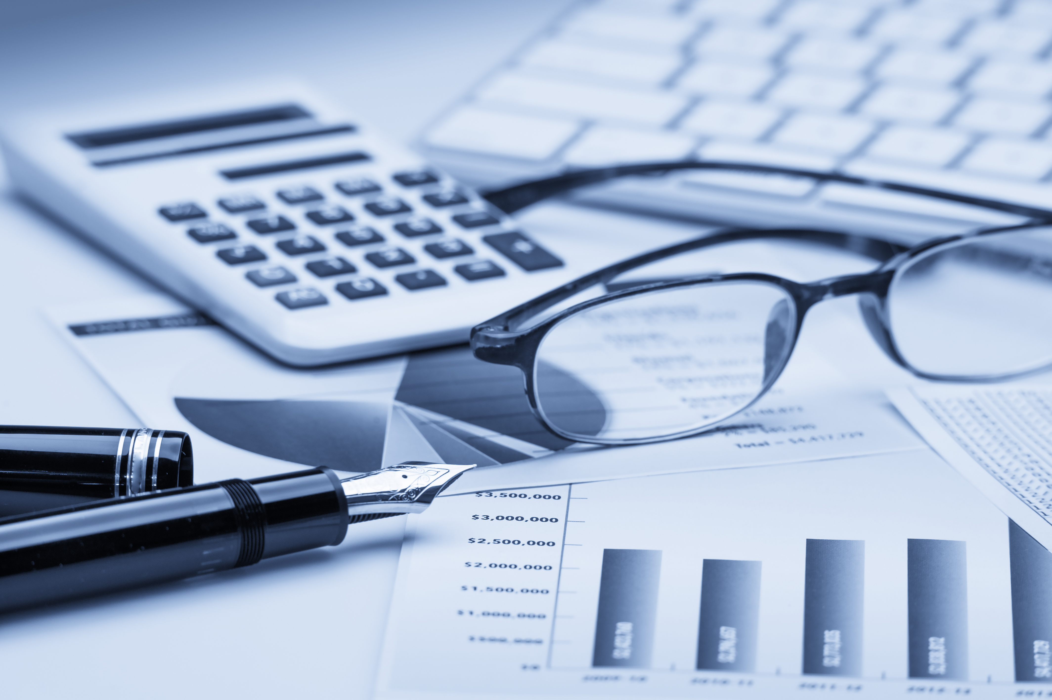 A calculator, a pen, and spectacles on top of financial records