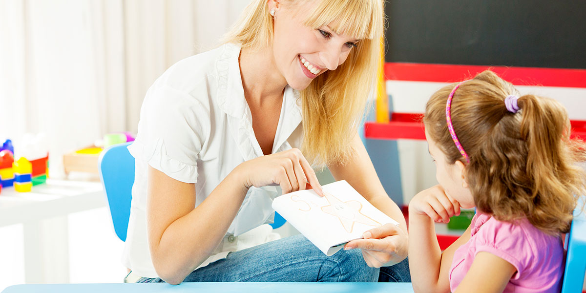 A female teacher helping a toddler to read