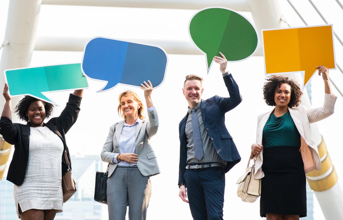four people holding up speech bubbles