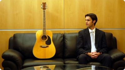 Businessman sitting beside a guitar