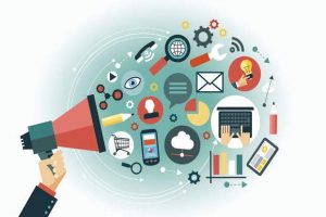 A hand holding a bullhorn which is spreading digital media services (laptops, charts, phones, messages, searchers, wifi, media tools)
