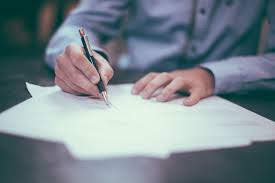 A person writing with a pen in white paper