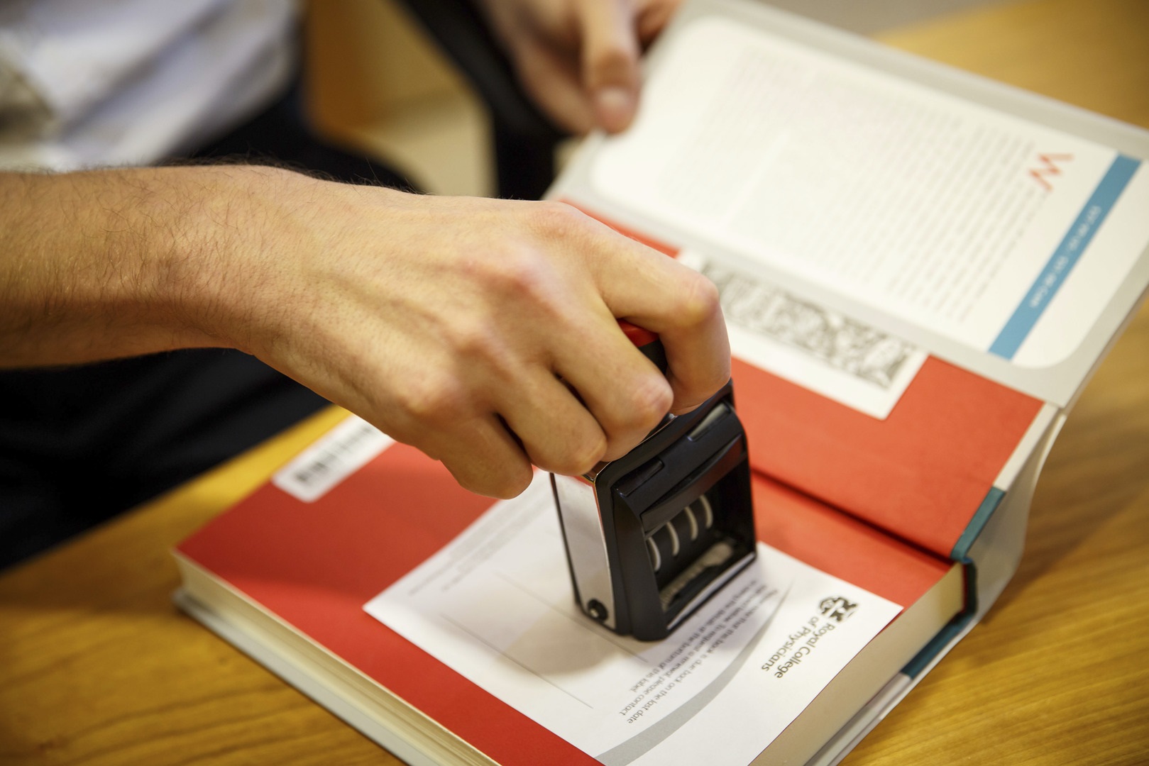 A librarian stamping a book when a student is borrowing it.