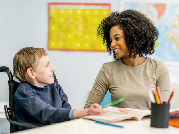 A girl helping a disabled student in work