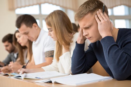 Worried student. Young handsome student guy looking stressed and nervous rubbing his temples during university exam tired headache session education thinking hardworking deadline annoyed concept