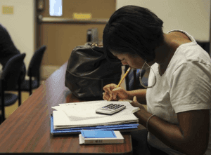 woman writing on a book with a calculator