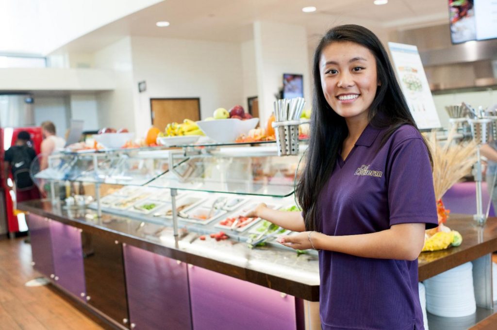 A girl standing at fresh salad bar