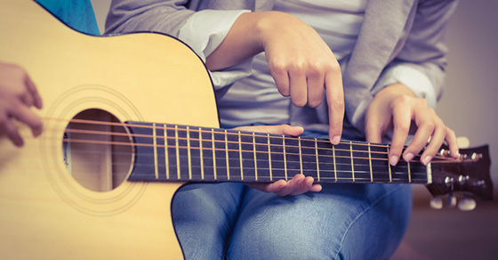 A person learning how to play a guitar