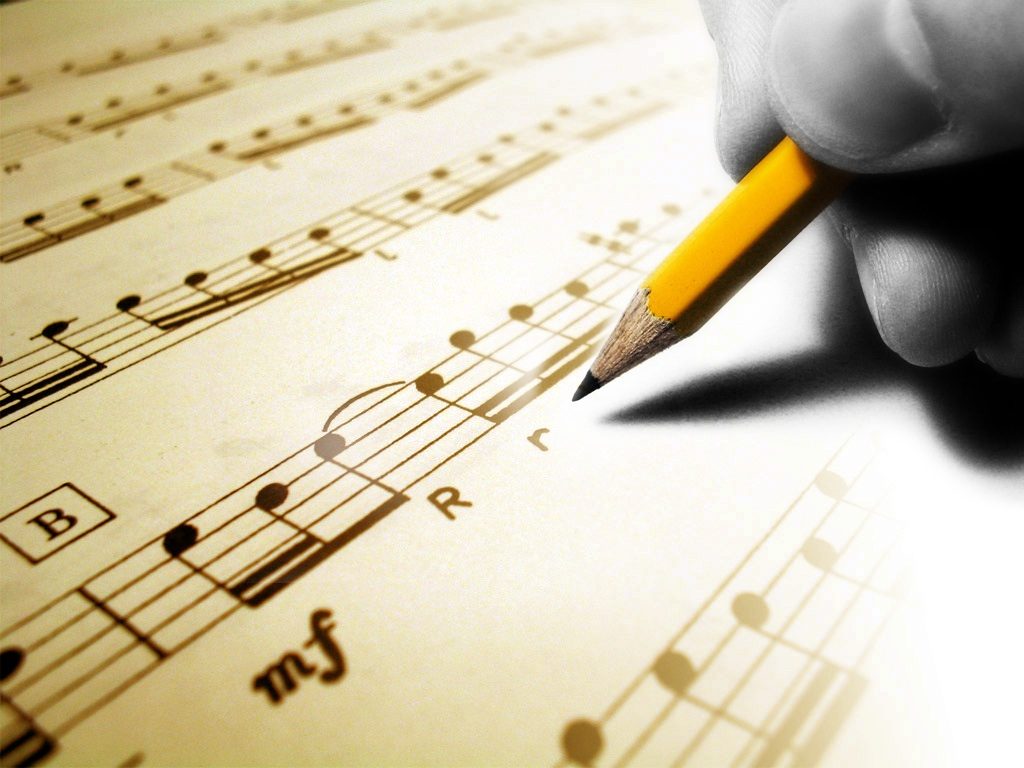 A person holding a pencil writing on music notes