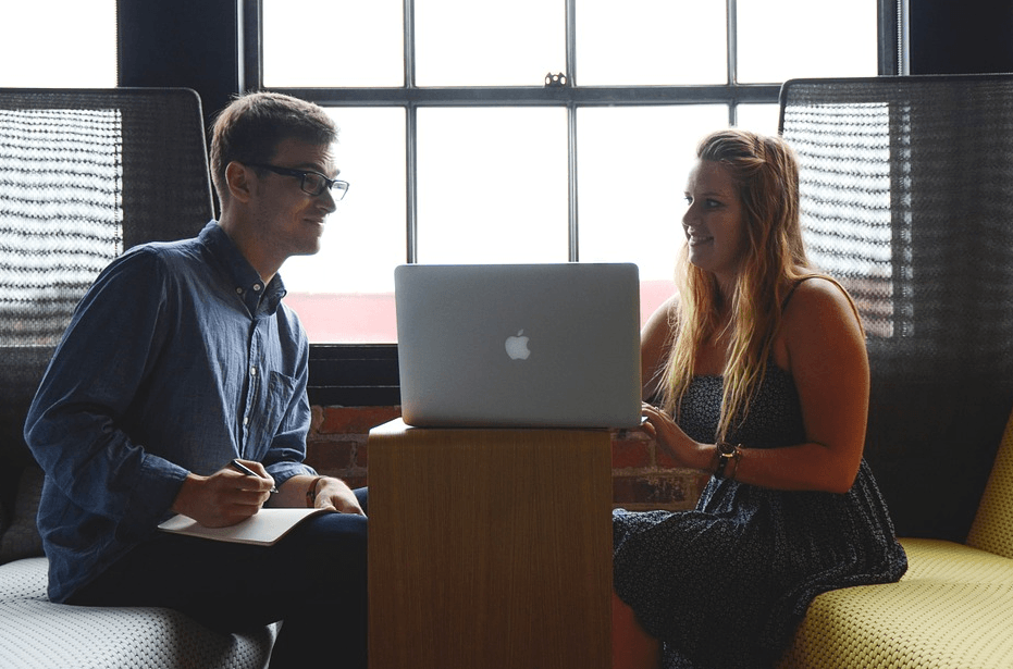 two people talking in front of a laptop