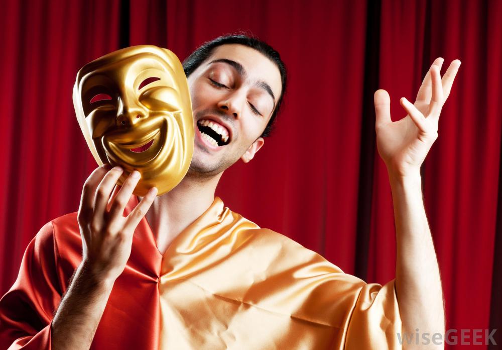 A male actor holding an acting mask in front of a red curtain