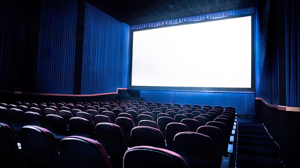 A cinema hall with a wide screen and seats