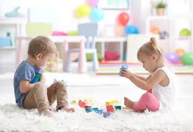 Two toddlers playing with toys on a floor