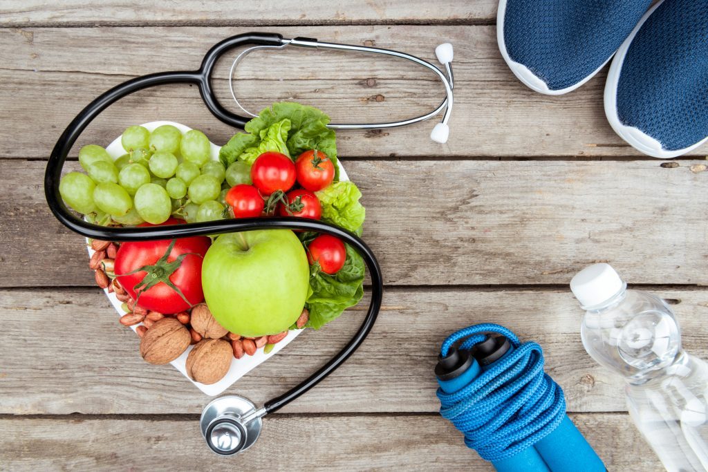 A Stethoscope, a bowl of fruits, a skipping rope, a bottle of water and a pair of sneakers
