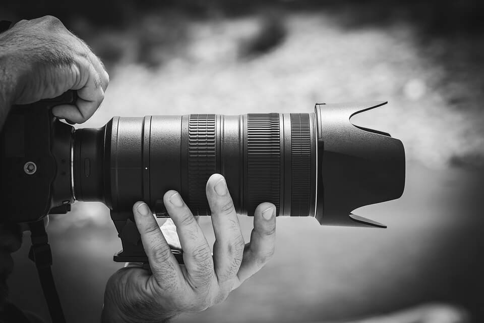 A black and white image of a person holding a camera