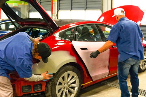 Two men working repairing a car's body