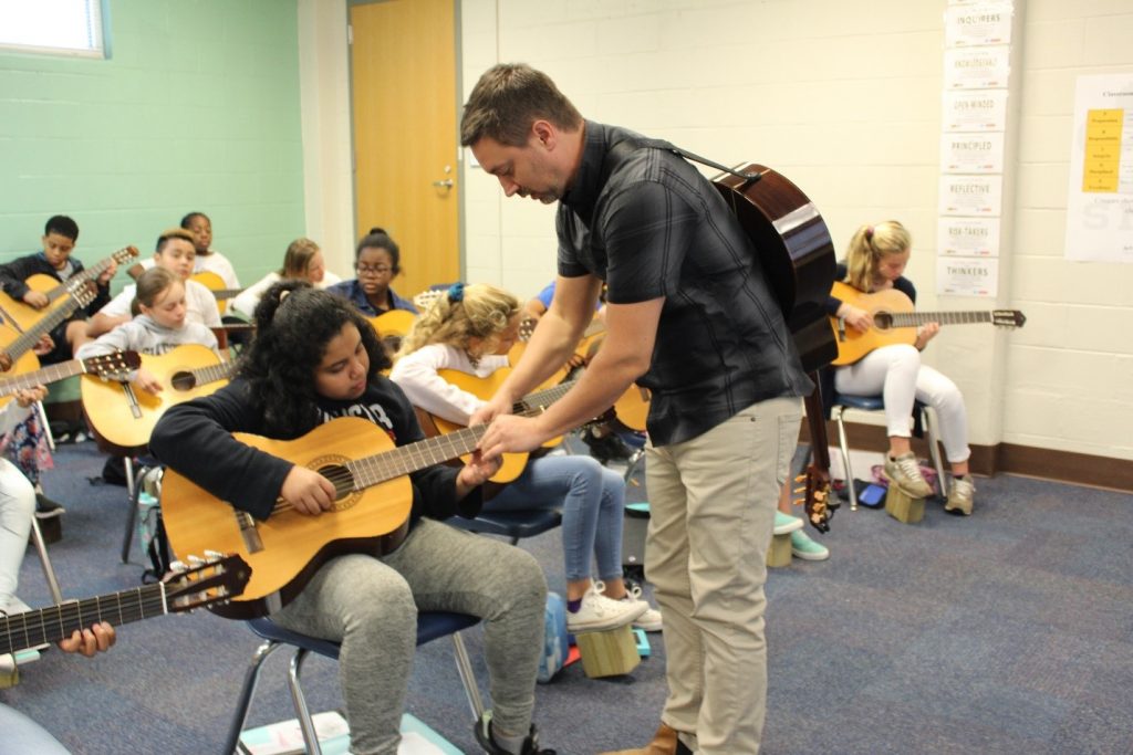 A music instructor teaching a guitar class