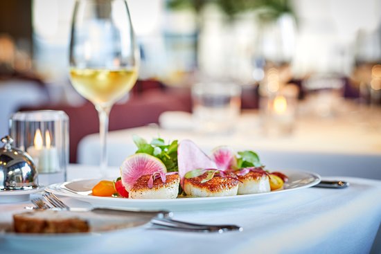 A set table with food on a plate and a glass of wine