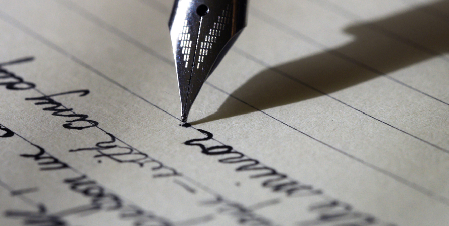 A pen with black ink writing on a paper