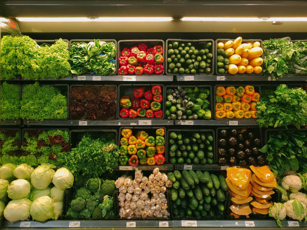 produce aisle in a grocery store filled with vegetables and fruits and other healthy foods