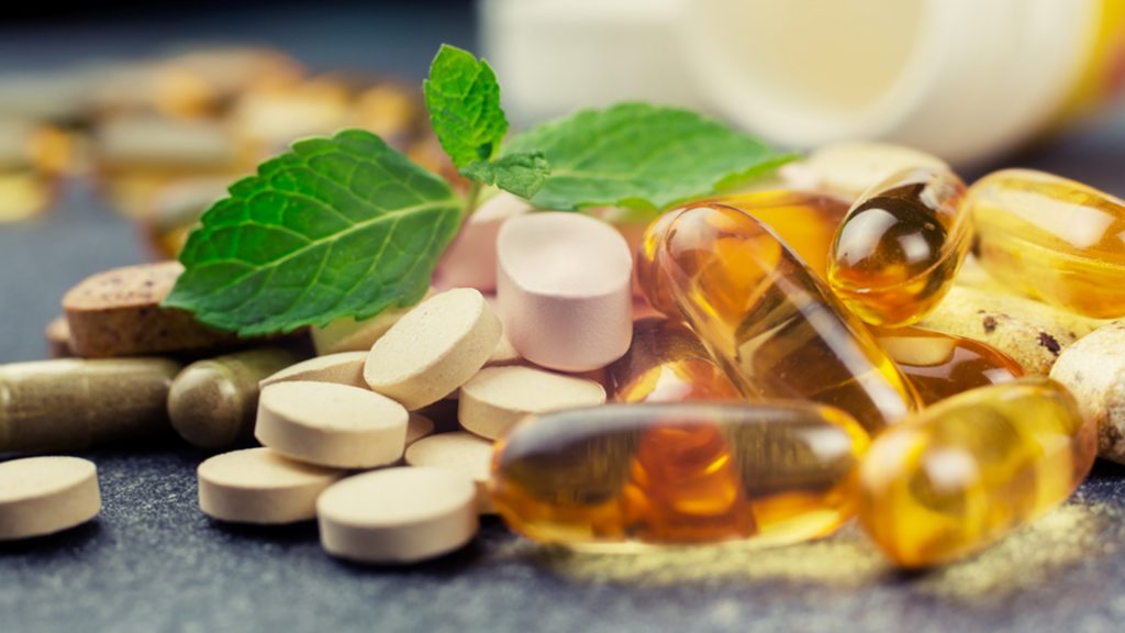 pills and health products on a pile with a green plant in the middle