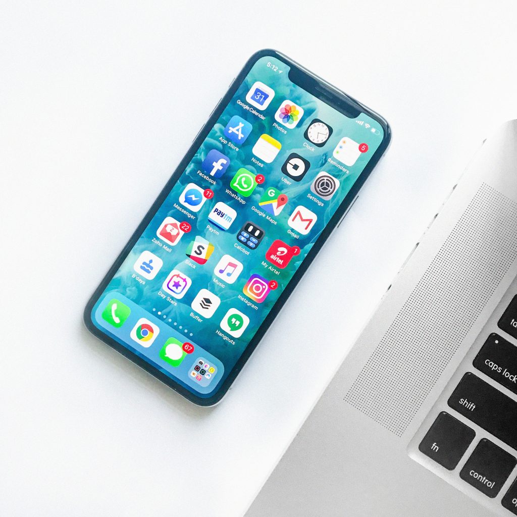 iphone cell phone sitting on a table beside a student's macbook