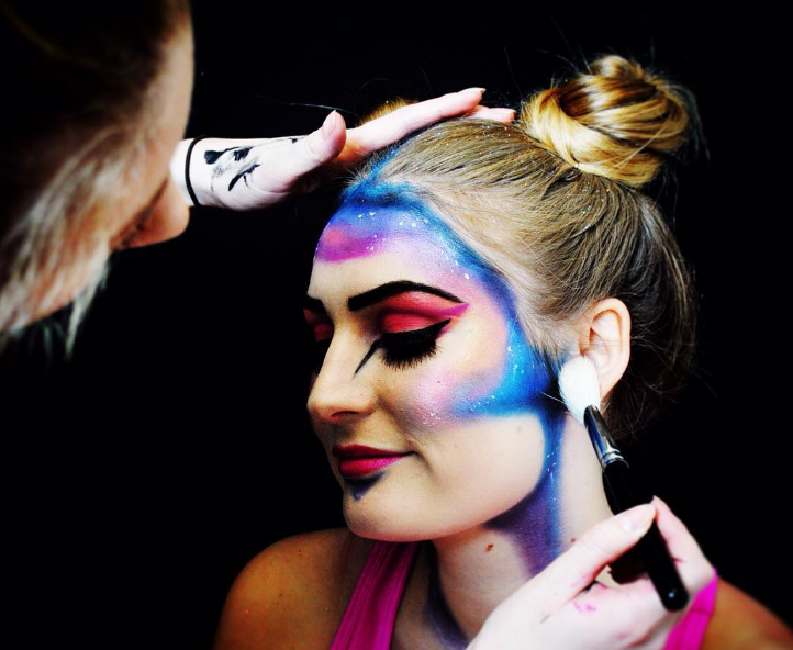 A female performer being applied make-up on her face