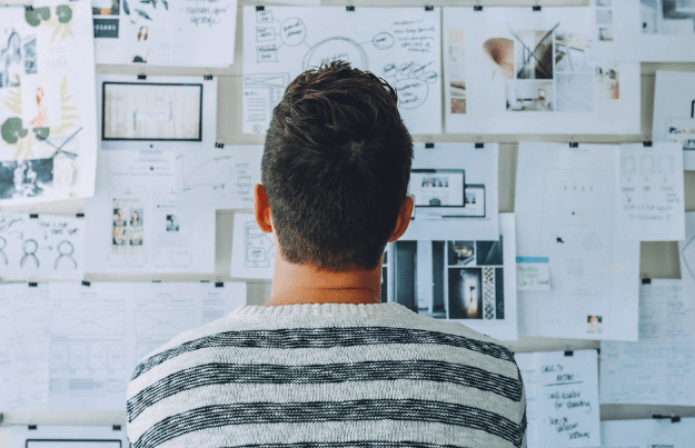 man looking at various documents pasted on the wall