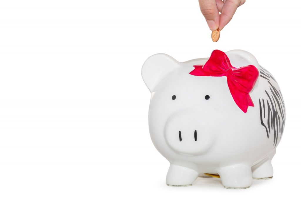person inserting a coin into a piggy bank to save money as a college student