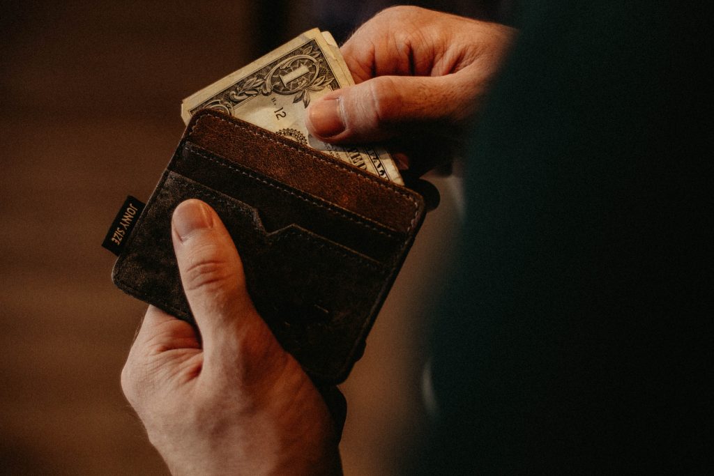 male student taking US dollar bills out of his wallet