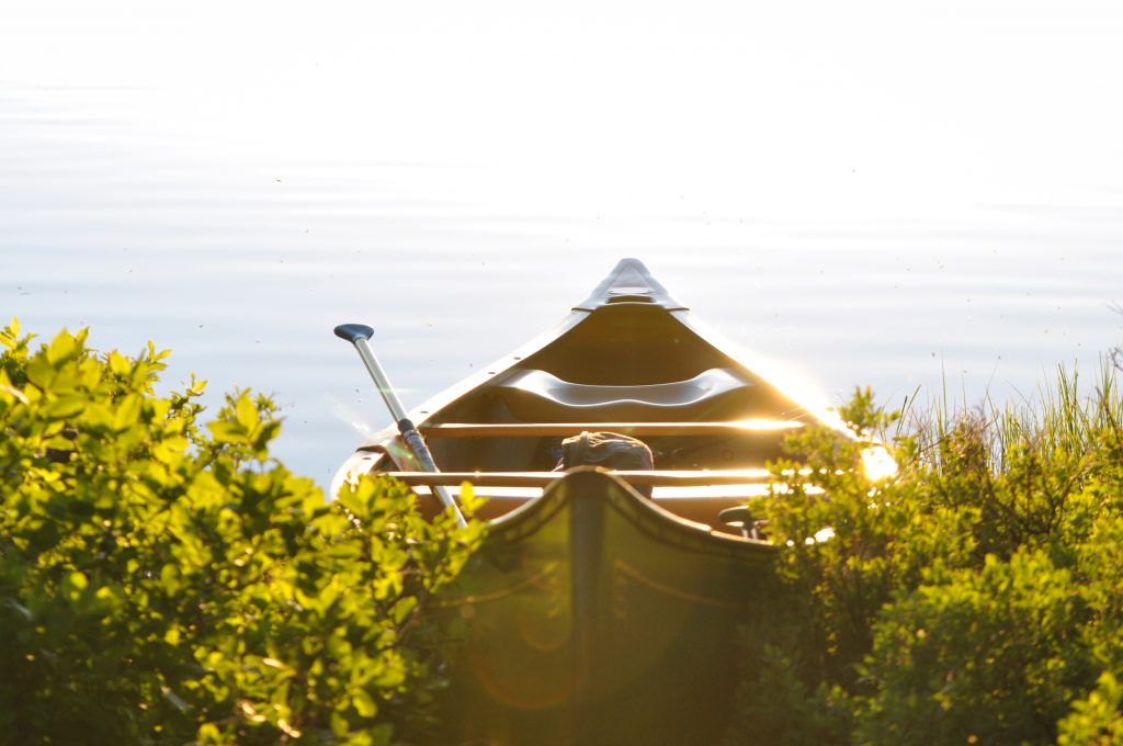 empty canoe parked on shore on a bright summer day