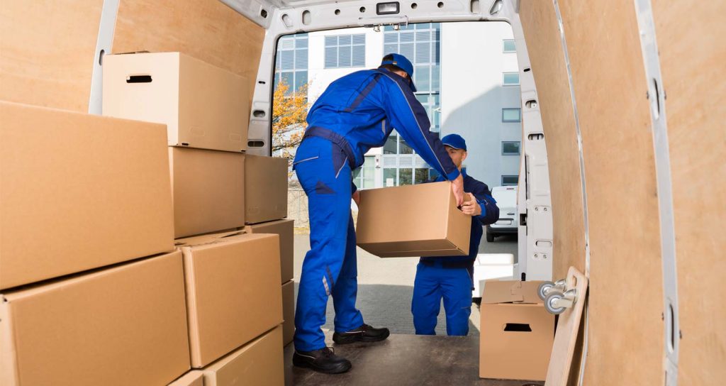 movers in blue uniforms moving boxes out of a moving truck