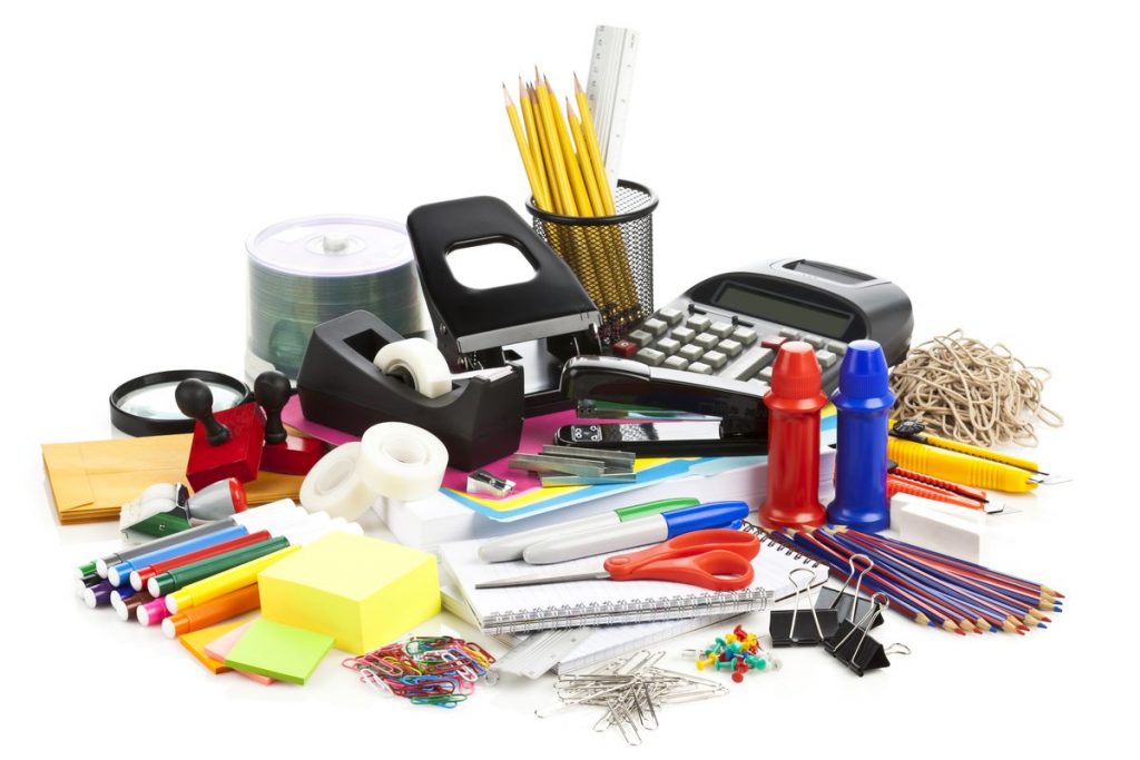 A pile of office or school supplies such as markers, tape, pens and pencils, paper, calculators, etc.