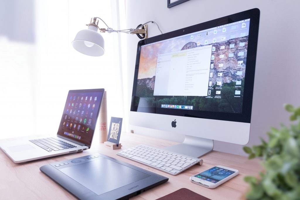technology products like a laptop, desktop and phone on a table