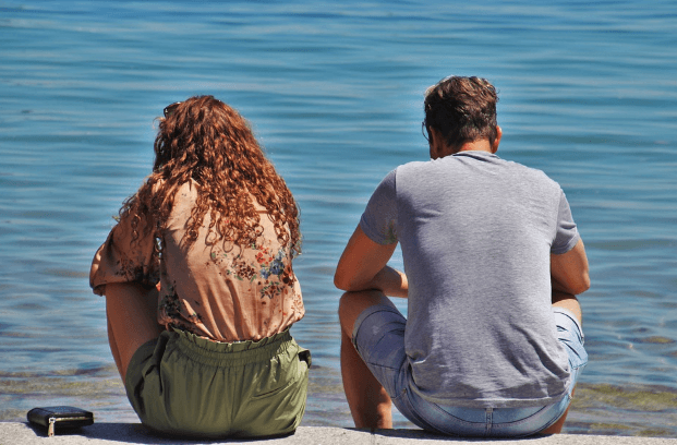 woman and man sitting on the beach not talking with each other