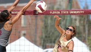 a person grabbing at the volleyball on the beach