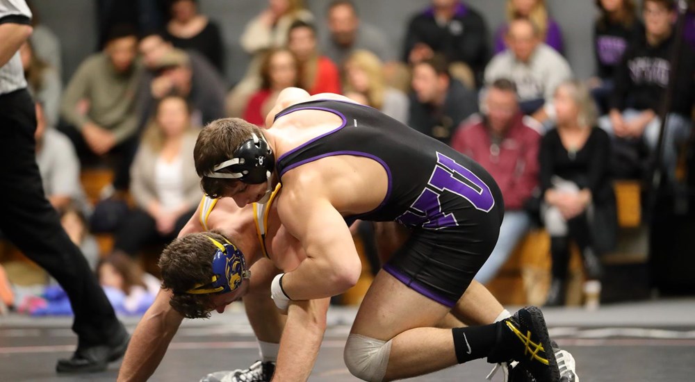 An NYU wrestler tackling an opponent
