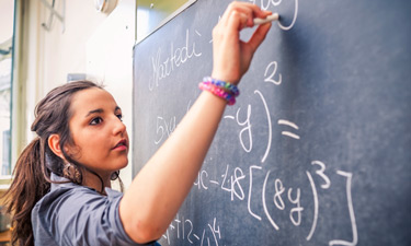 Student solving a math problem on the board.