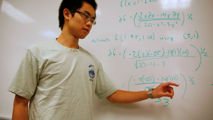 Student reviewing a math problem on the board.