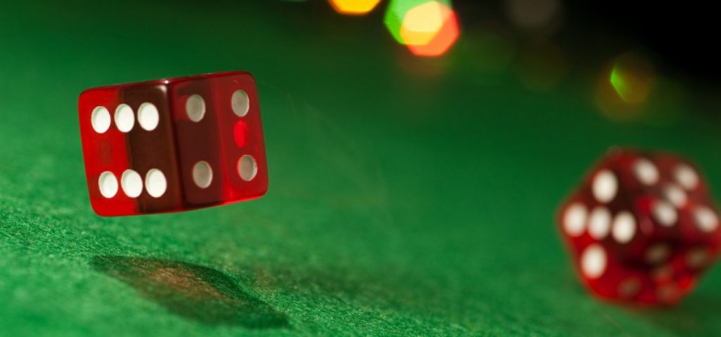 A pair of red dice rolling on a green felt table