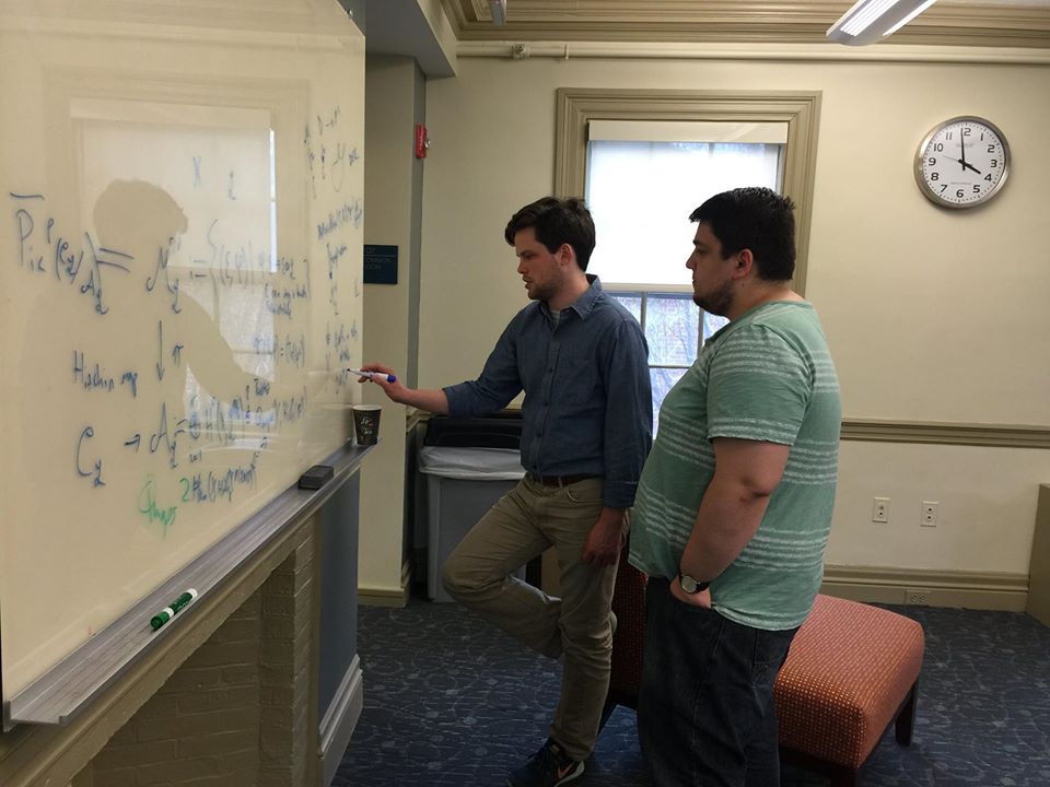 A math professor explaining a math problem to a student on a white board