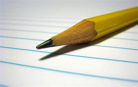 A pencil laying on top of lined paper.