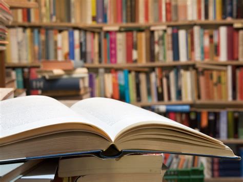An opened book with a bookshelf in the background.