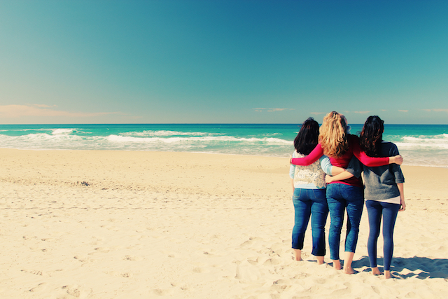 a group of friends watching the shoreline at the beach