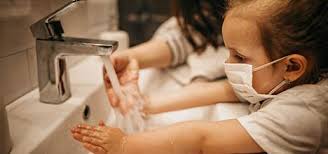 kids washing their hands while wearing masks