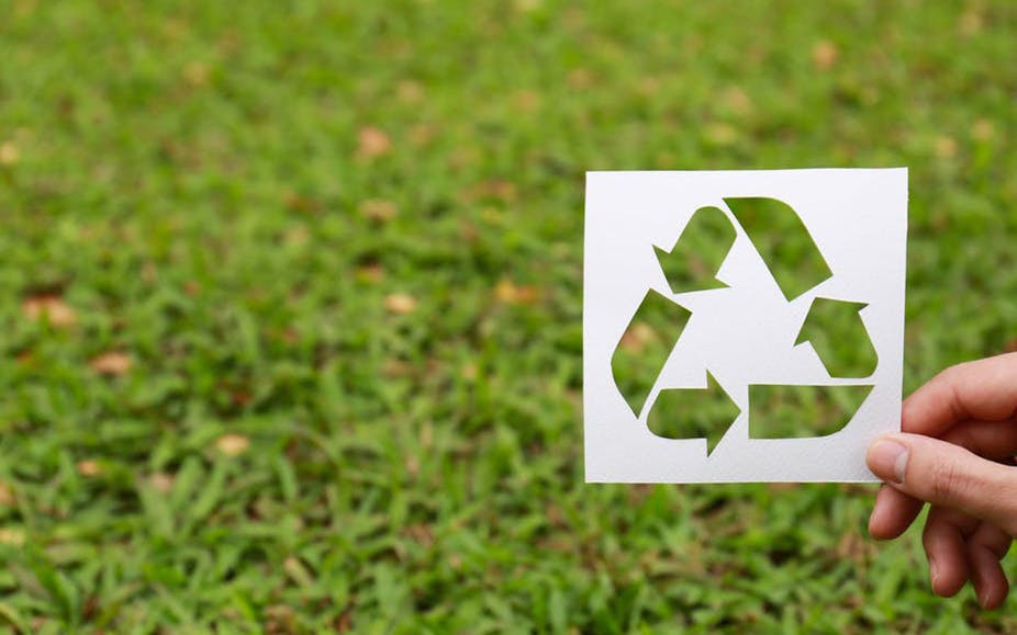 the recycling symbol in front of grass